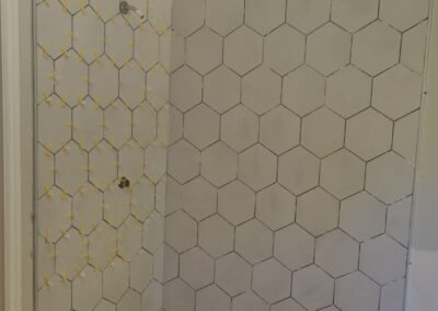 Bathroom showing a completed hexagon tile installation on the floor and shower walls, without grout.