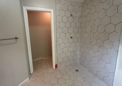 A collage of bathroom photos showcasing the installation of hexagonal tiles with grout. The images highlight different angles of the tiled floor and shower walls, displaying the even distribution of grout between the tiles, creating a smooth and professional finish. The light from a nearby window illuminates the bathroom, enhancing the contrast between the tiles and the newly applied grout.