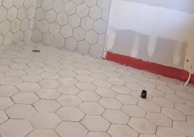 Progress of hexagon tile installation on shower walls, featuring clean lines and geometric design.