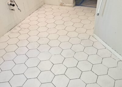 A modern shower wall and floor with hexagon tiles installed, ready for grouting.